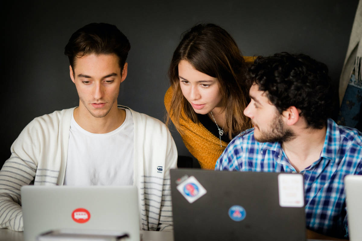 Three people with two laptops