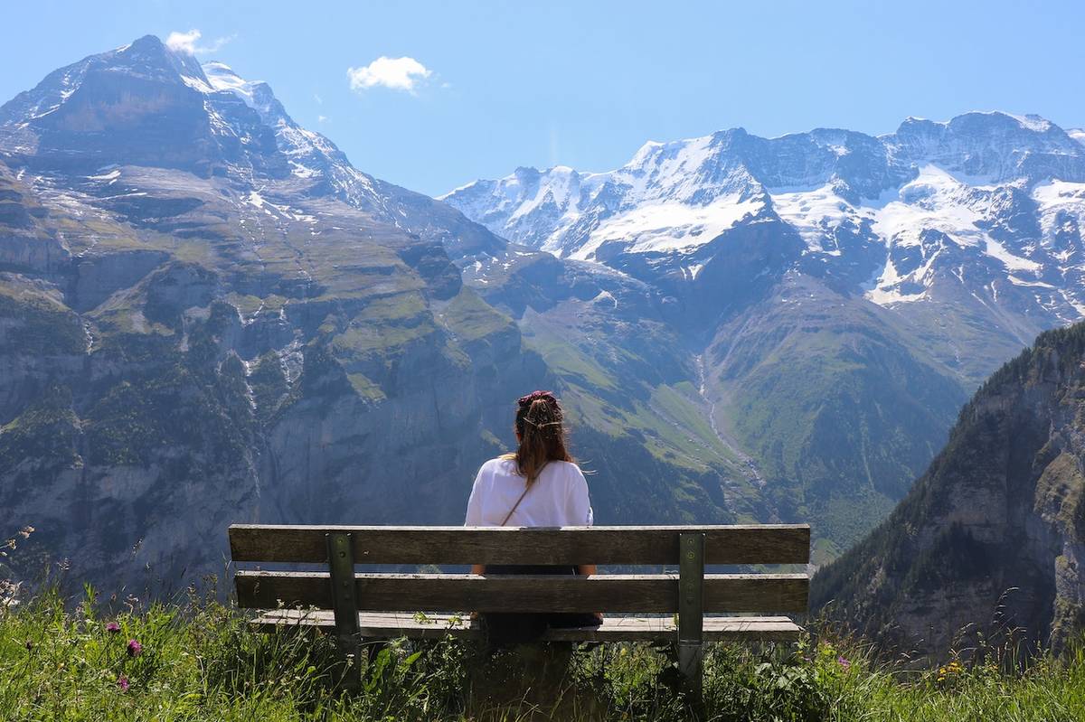 Woman sitting on bench looking at mountains in Switzerland